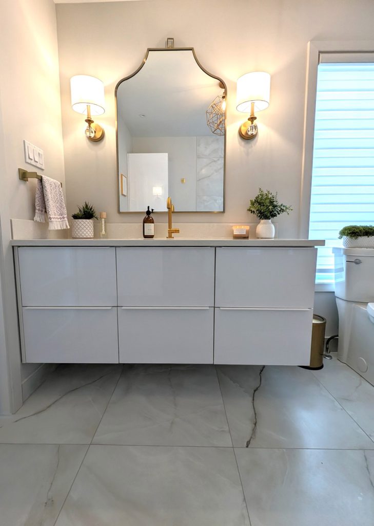 Floating gloss vanity with arched mirror, gold fixtures, and soft natural daylight — designed for a serene spa-like experience.