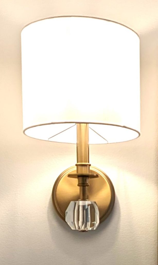 Brass wall sconce detail adding warm ambient lighting to a high-end bathroom