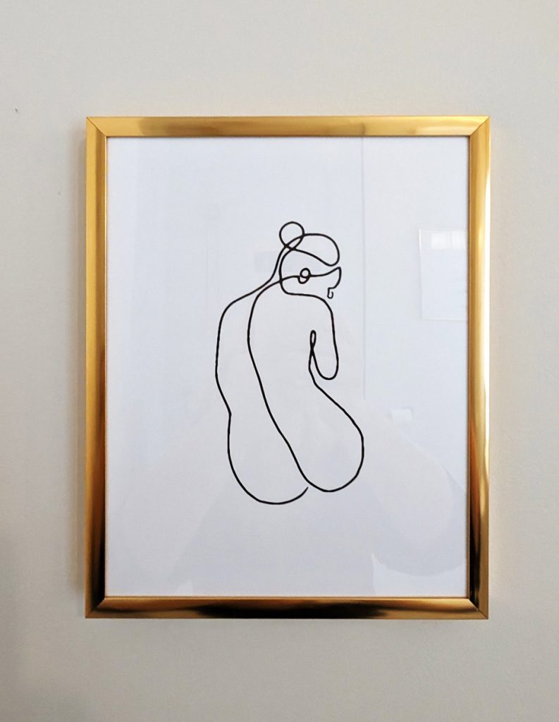 Framed minimalist artwork with gold frame adding sophistication to luxury en suite