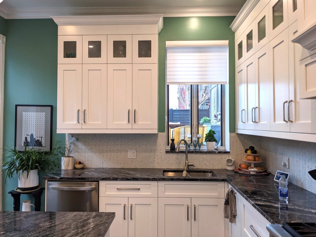 Elegant kitchen detail with white shaker cabinetry, granite countertops, green accent wall, and refined natural light — from Lucie Pitt’s Westmount Elegance project.