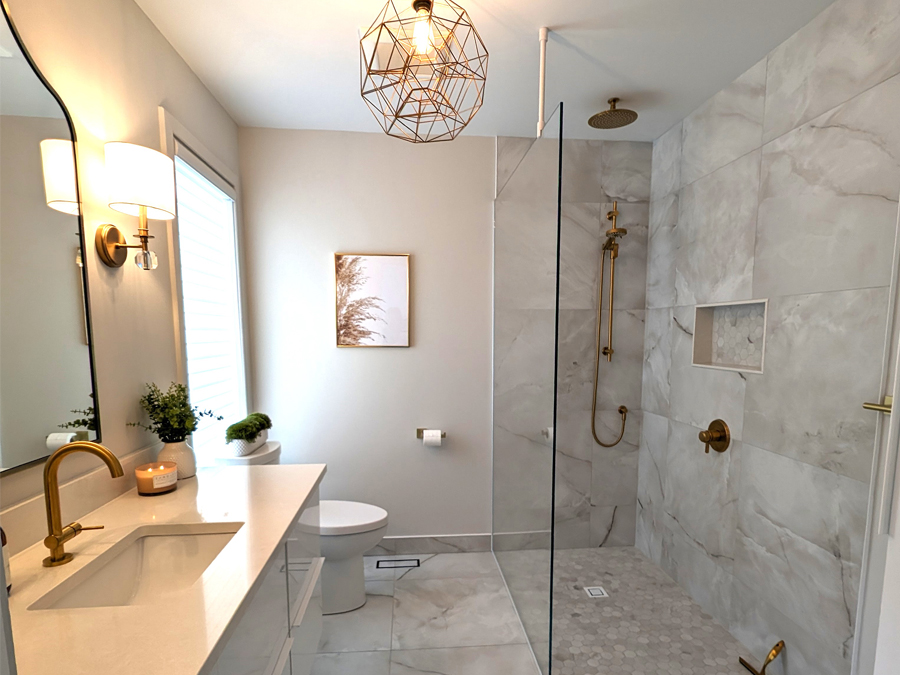 High-end marble bathroom with gold rain shower, glass partition, and refined modern finishes.