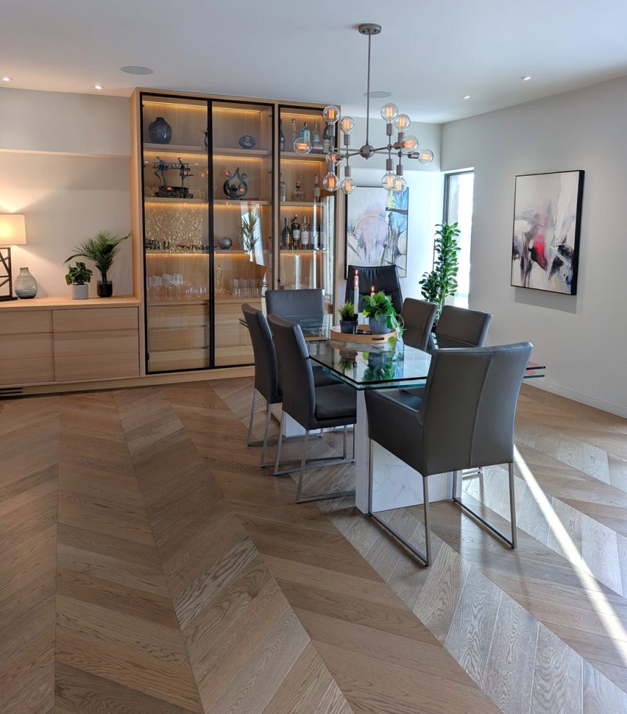 Elegant dining area with glass table, modern chandelier, and illuminated oak display cabinets — Lucie Pitt’s Habitat 67 design.