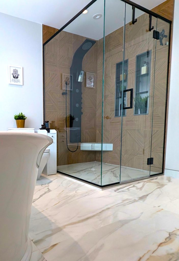 Elegant glass shower enclosure with black hardware, wood-look tile, and clean minimalist detailing — Lucie Pitt’s Laval Harmony master bathroom.