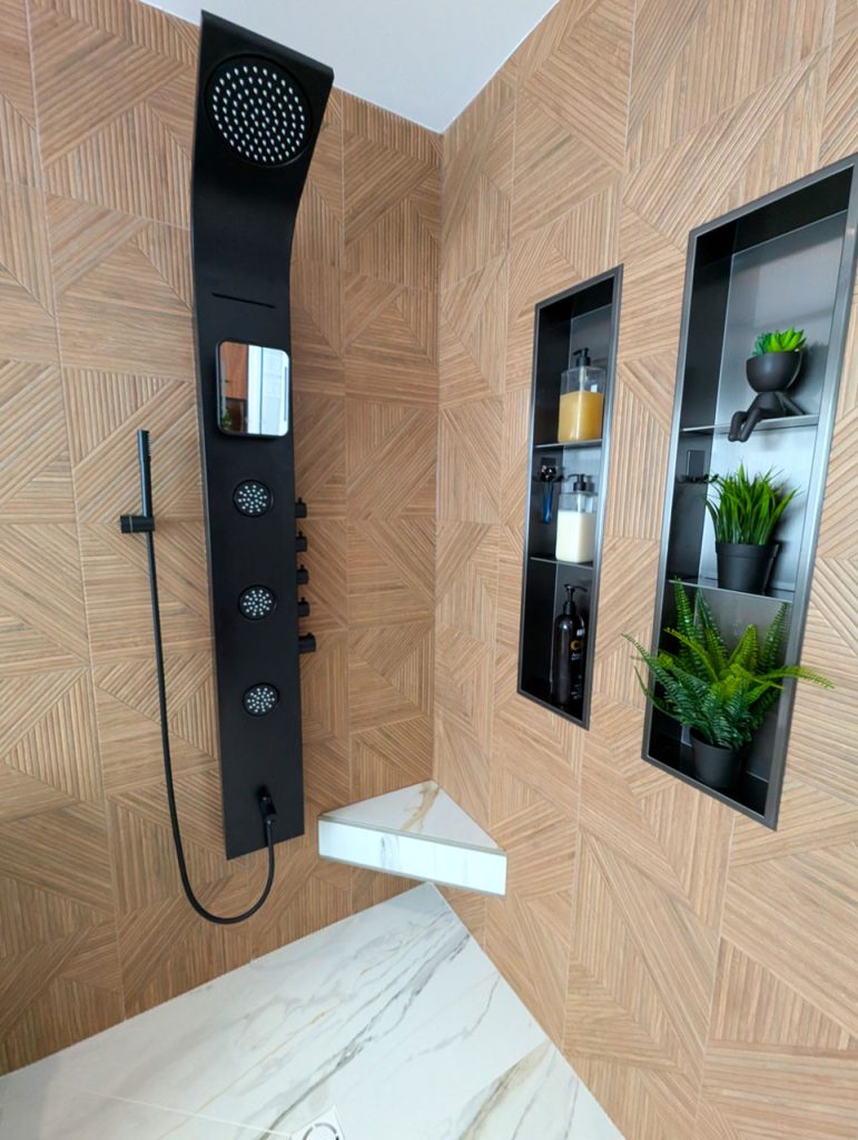 Modern shower panel with matte-black controls, geometric wood-look tile, and recessed plant niches — Laval Harmony bathroom by Lucie Pitt.