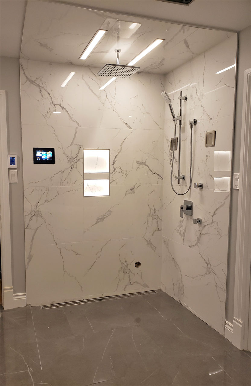 Luxurious marble-look steam shower with digital controls, rainfall showerhead, illuminated niches, and sleek chrome fixtures — a modern spa retreat by Lucie Pitt.