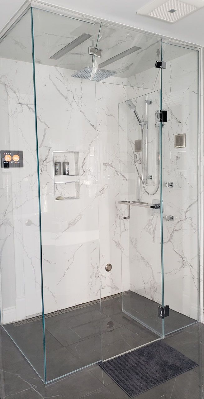 Modern glass-enclosed shower with marble-look porcelain tiles, rainfall head, and chrome fixtures — serene spa atmosphere.