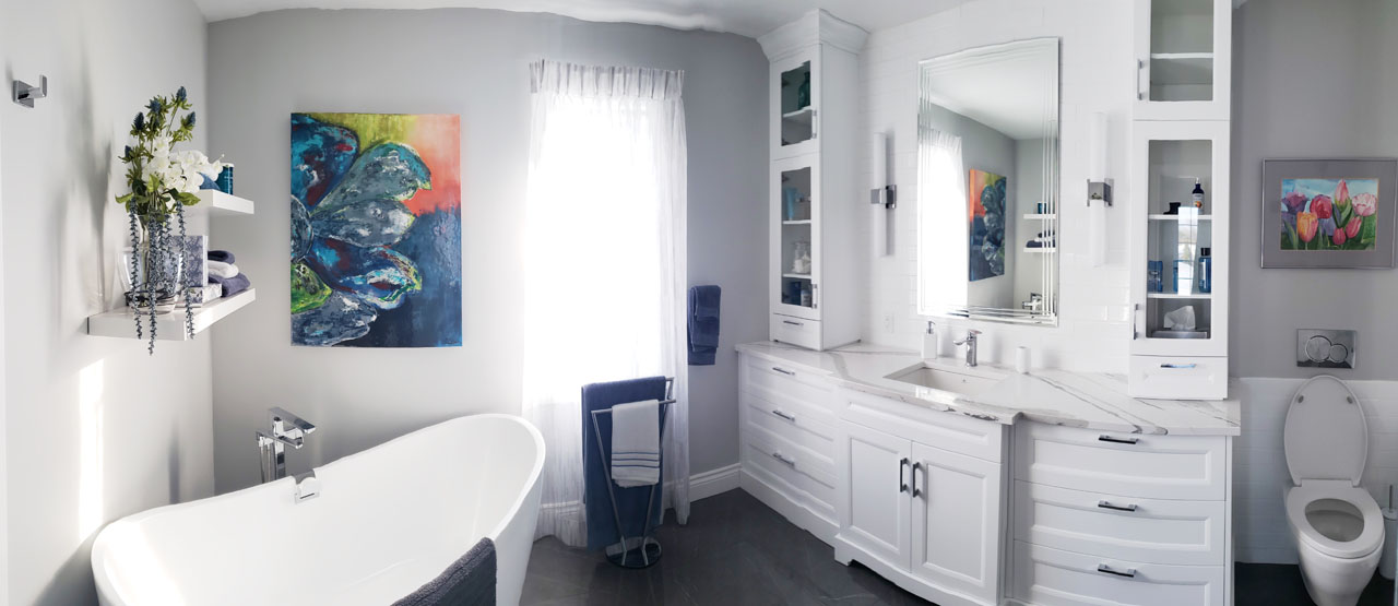 Bright contemporary bathroom with freestanding tub, built-in white cabinetry, large mirror, and bold abstract artwork — designed by Lucie Pitt.